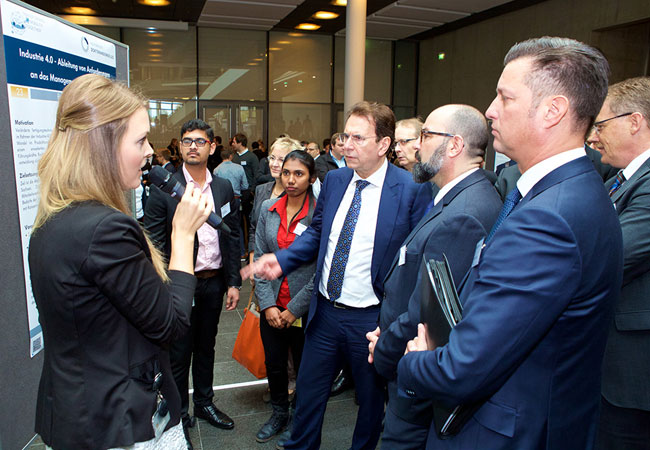 Pressebild: Dr. Karlheinz Blessing, Vorstand für Personal, Organisation und IT (in der Bildmitte), Stephan Wolf, stellvertretender Vorsitzender des Konzernbetriebsrats, und Thomas Schmall, Vorstand Konzern Komponente, im Gespräch mit der Doktorandin Barbara Theresia Wulfken.