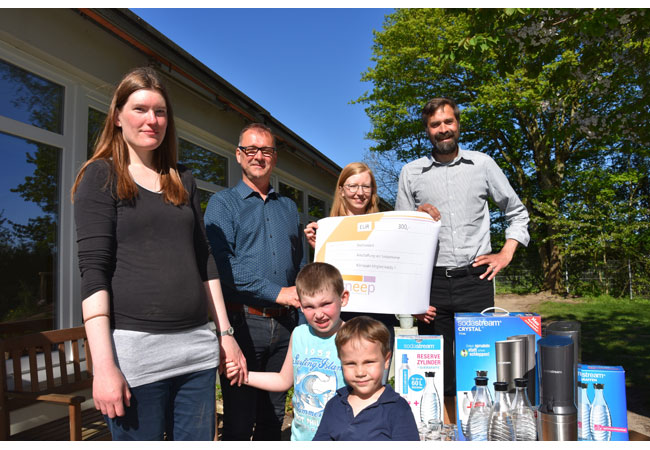 Sie freuen sich über die gespendeten klimaschonenden Sodastreamer: Henning Brüggemann (Klimapakt-Vorsitzender) Annika Frahm (sneep-Lokalgruppe Flensburg), Heiko Frost (Geschäftsführer Adelby 1) (v.r.n.l.) sowie Daniela Erichsen mit Sohn Torben und Lukas Merten (alle Besucher der Kita Preesterbarg).