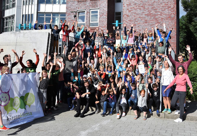Bildunterschrift: Henning Brüggemann (Klimapakt-Vorsitzender, vorne links auf der Treppe sitzend) freut sich über das große Engagement für den Klimaschutz im Kreise der Projektakteure und Schüler der Falkenbergschule, Schule Friedheim, Grundschule Adelby, Paulus-Paulsen-Schule sowie der Grundschule Ramsharde.