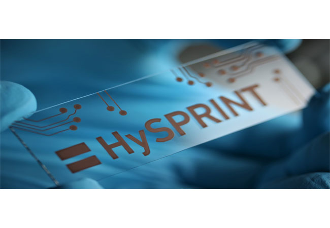PB: Das aus einer Kupferlösung aufgedruckte HySPRINT-Logo (Helmholtz Innovation Lab) symbolisiert, wie sich dünnste Materialschichten kostengünstig herstellen lassen. Mögliche Anwendungen sind Solarzellen, organische LEDs und Transitoren. Herstellung und Foto: Humboldt-Universität zu Berlin/List-Kratochvil