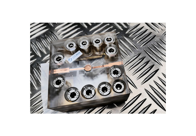 PB: Testaufbau für die Festkörperbatterie: Die Batterie von der Größe einer Knopfzelle befindet sich in der Mitte des Plexiglasgehäuses, welches die dauerhafte Kontaktierung der Batterie sicherstellt. / Forschungszentrum Jülich / Regine Panknin