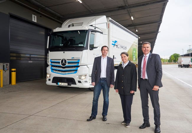 PB: Dr. Thomas Grobel, Leiter der Logistikplanung im Mercedes-Benz Werk Mannheim (links), übergibt den vollelektrischen eActros an Marie-Elizabeth Benois, Gesellschafterin der Pfenning-Gruppe, und Matthias Schadler, Geschäftsführer von Pfenning Logistics.