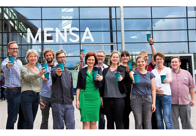 PB: Bildunterschrift: Simone Lange (Oberbürgermeisterin und Klimapakt-Vorstand, Bildmitte/grünes Kleid) gibt – zusammen mit vielen Kooperationspartnern – den Startschuss für das Flensburger Mehrwegbechersystems auf dem Campus-Gelände.