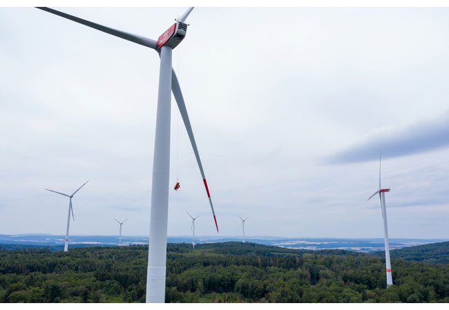 PB: Die Rettung eines Verunglückten aus der Gondel einer Windkraftanlage in 140 Meter Höhe stellt auch erfahrene Feuerwehrleute vor Herausforderungen. Umso wichtiger ist es, den Ernstfall regelmäßig zu üben – so wie dieser Tage im Taunus-Windpark Weilrod. Winzig erscheint die Trage mit Björn Orth zwischen Turm und Rotorblatt.