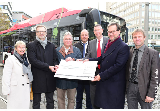 PB: Staatssekretär Florian Pronold überreichte den Vertretern der Nürnberger Verkehrsgesellschaft einen Scheck mit knapp 24 Millionen Euro für die Anschaffung von Elektrobussen. / Copyright: BMU/Claus Felix