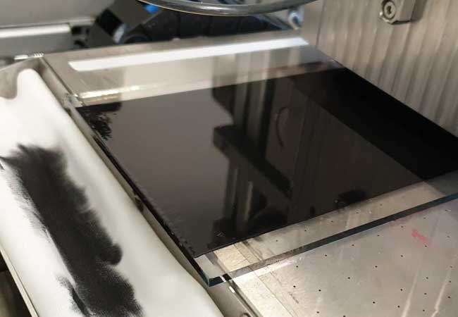 PB: Die Schlitzdüse bringt eine Kohlenstoffschicht auf das Glassubstrat auf. Nacheinander können so alle fünf Schichten der Solarzelle aufgebracht und gemeinsam getrocknet werden. Beim herkömmlichen Siebdruck-Verfahren musste jede Schicht mindestens eine Stunde separat getrocknet werden. Bild: Empa