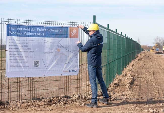 PB: EnBW Mitarbeiter Michael Matthes befestigt das Bauschild vor Ort_KLE