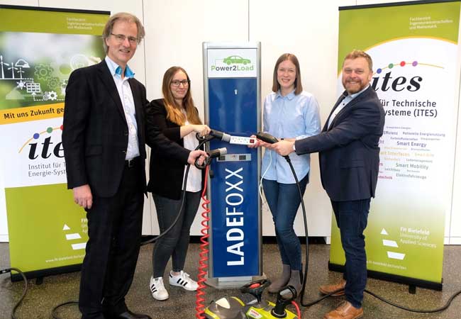 PB: FH Bielefeld University of Applied Sciencesschließen Zwei Frauen und zwei Männer stehen an einer Ladesäule für Elektroautos und halten Ladekabel an eine Mehrfachsteckdose Die Projektpartner von Power2Load: Dr. Peter Westerbarkey (Westaflex GmbH), Julia Eberharter (Archimedes Technik GmbH), Katrin Schulte (FH Bielefeld) und Prof. Dr.-Ing. Jens Haubrock (FH Bielefeld) (v.l.n.r.) / Foto: Sarah Heise