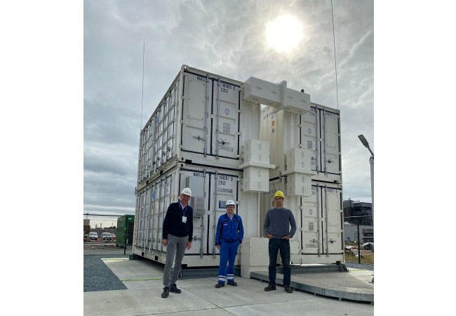 PB: Die BASF New Business GmbH (BNB) hat ein System aus vier NAS® Batterie-Containern in das Stromnetz des BASF-Verbundstandorts Antwerpen eingebunden und erfolgreich in Betrieb genommen. Das gemeinsame Team von BNB und BASF Antwerpen vor dem NAS® System in Antwerpen: Frank Prechtl / BNB, Andreas Wastyn / BASANT, Florian Dötz / BNB Die Abstandsregeln wurden beachtet, eine Mund-Nasen-Maske war nicht erforderlich. Die Nutzung von Sicherheitsbrillen war in diesem Bereich nicht vorgeschrieben.