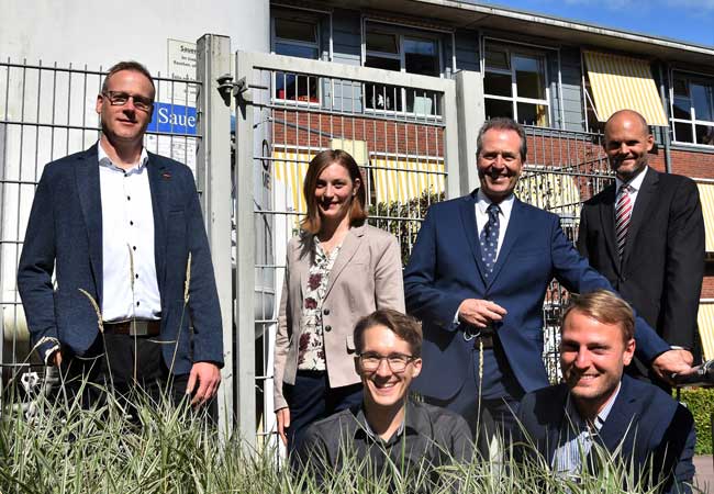 PB: Ein erfolgreiches Projektteam: Thomas Flemig (Technischer Leiter, Malteser), Samanta Weber (wiss. Mitarbeiterin, Hochschule Flensburg), Jürgen Freitag (Leiter Immobilien, Bau und Technik, Diako-Krankenhaus) und Prof. Dirk Volta (Projekteiter, Hochschule Flensburg) (v.l.n.r. stehend) sowie (vorne sitzend von links) Ruben Harten und André Lindemann (beide Projektingenieure, Hochschule Flensburg). Links im Hintergrund: Der Sauerstofftank für das Diako-Krankenhaus.