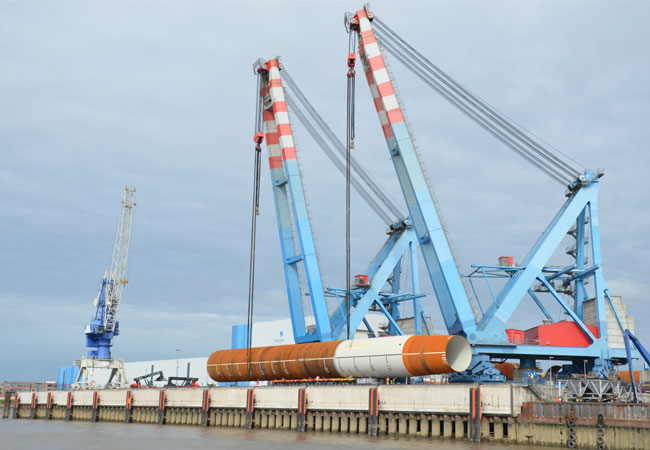PB: Ein Monopile wird in Steelwinds Hafen von Nordenham verladen. Er wiegt 1 450 t, ist 83 m lang und hat einen Durchmesser von 8 m. Die rostbraunen Teile sind unbeschichtete Stahl-Oberflächen, die hellen korrosionsschutzbeschichtete Flächen. / Foto: Ralf Hubo / © Dillinger
