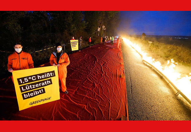 PB: Mit einer symbolischen roten Linie zwischen der Ortschaft Lützerath und Garzweiler protestieren Greenpeace-Aktivist:innen gegen die Zerstörung des Dorfes durch den Kohlekonzern RWE.