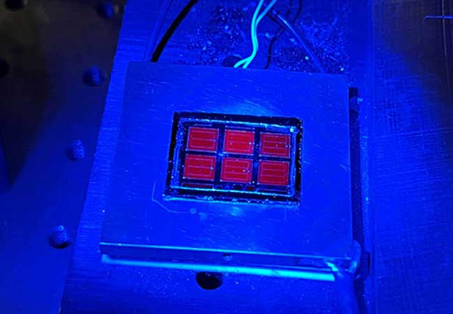 PB: The record-setting solar cell shines red under blue luminescence. Photo by Wayne Hicks, NREL