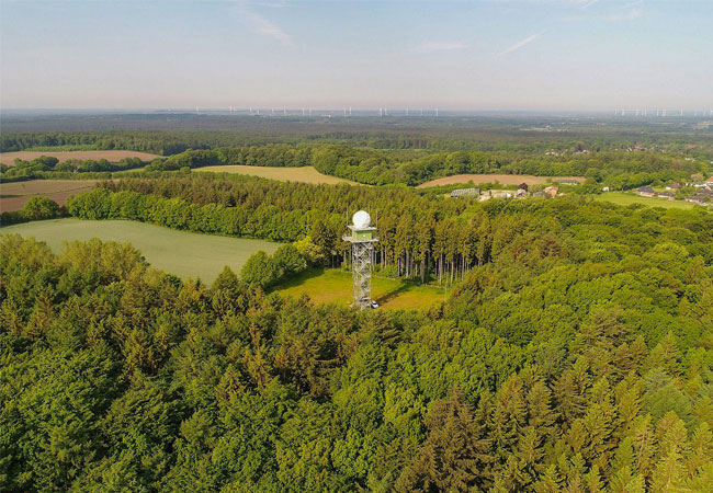 PB: Der Wetterradarturm des Deutschen Wetterdienstes in Boostedt (Schleswig-Holstein). Im Hintergrund in der Schutzzone von 5 bis 15 km Entfernung Windenergieanlagen. © DWD