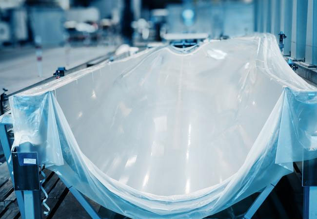 PB: Die flexible vakuum-streckgezogene PeelPLAS®-Trennfolie schmiegt sich wie eine zweite Haut in die 18 m lange Rotorblattsegmentform und ermöglicht nach Fertigung des FVK-Großbauteils dessen trennmittelfreie Entformung