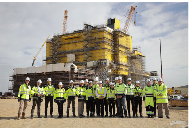 Pressefoto: TenneT-COO Tim Meyerjürgens mit den Partnern Siemens Energy und Dragados Offshore und der Besuchsgruppe rund um Janecek, Koordinator*in der Bundregierung für Maritimes und Tourismus. Im Hintergrund die Konverterplattform BorWin epsilon, die aktuell in Cádiz gebaut wird.