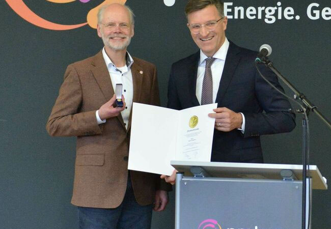 PB: : Peter Götz, Vorstand des Genossenschaftsverbands - Verband der Regionen (rechts), zeichnet Andreas Neukirch für sein jahrzehntelanges Engagement für das Genossenschaftswesen mit der Goldenen Ehrennadel des Genossenschaftsverbandes aus. Foto: Anne Dohmann/Prokon.