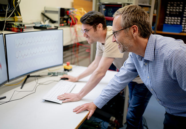 HM-Doktorand Oliver Kalmbach und Prof. Dr. Christoph Hackl (v.l.n.r.) arbeiten gemeinsam an einem stabilen Funktionieren der Mehrlevel-Umrichter (Foto: Alexander Ratzing)