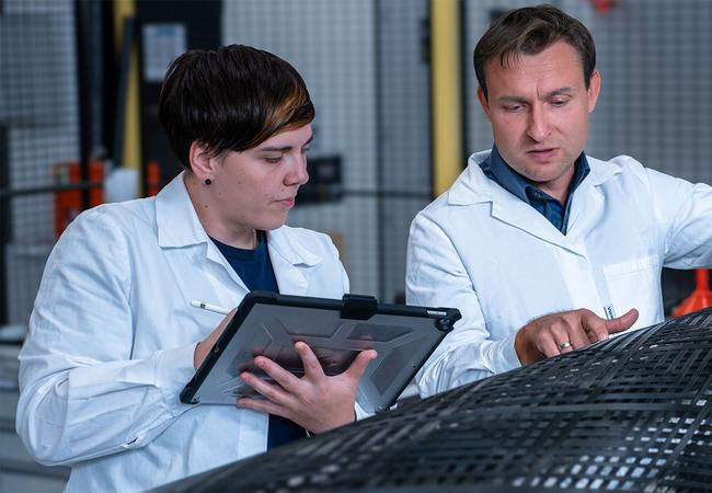 PB: Claudia Vogt und Dr. Mario Naumann vom Forschungsbereich „Carbonfaser- und Verarbeitungstechnologien“ untersuchen einen im Herstellungsprozess befindlichen rotationsförmigen carbonfaserverstärkten Leichtbaudruckbehälter im Faserverbundlabor. / ©: TU Chemnitz/Robert Wolf