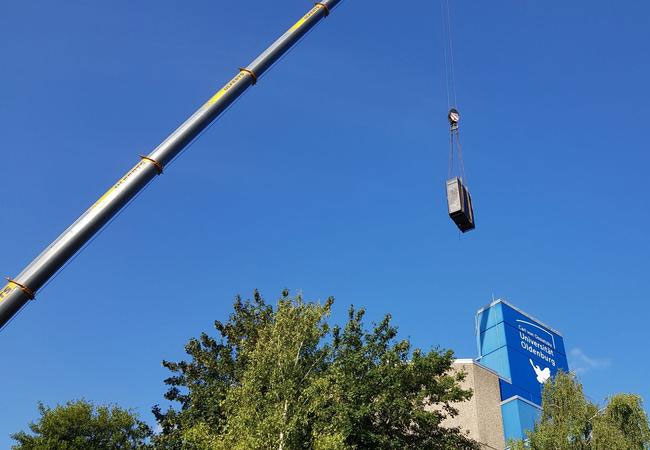 PB: Die Universität Oldenburg hat im vergangenen Jahr neue, wassergekühlte Hochleistungsrechner erhalten, die mit einem Kran angeliefert werden mussten. Die Abwärme der Server wird nun in das Wärmenetz der Universität eingespeist. / Universität Oldenburg /Stefan Harfst