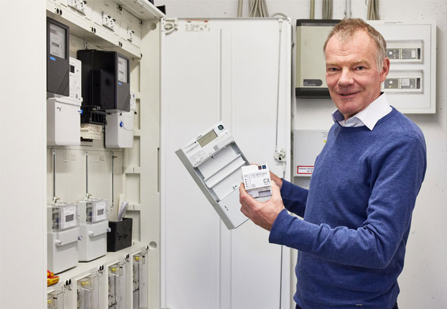 PB: Gero Lücking hält das Herzstück einer nachhaltigen, digital gesteuerten Stromversorgung in der Hand: Ein intelligentes Messsystem, das aus einem digitalen Stromzähler und einem Smart-Meter-Gateway besteht. / ©: Bildquelle: Oliver Roesler / Techem