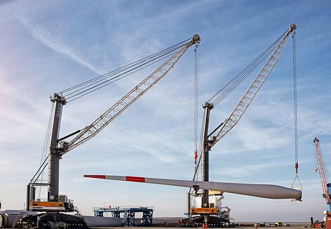 Liebherr: Im Hafen von Esbjerg können unsere LHM 600 und LHM 800 Hafenmobilkrane, ausgestattet mit dem Sycratronic Assistenzsystem, bis zu vier 12 MW Windblätter pro Stunde entladen. Diese fortschrittliche Technologie ermöglicht es einem einzigen Kranfahrer, zwei Krane zu steuern. Dank der eingebauten Sicherheiten ermöglicht das Sycratronic-System dem Kranfahrer die volle Ausnutzung der Lastkurve des Krans, während diese normalerweise auf 75% beschränkt ist.