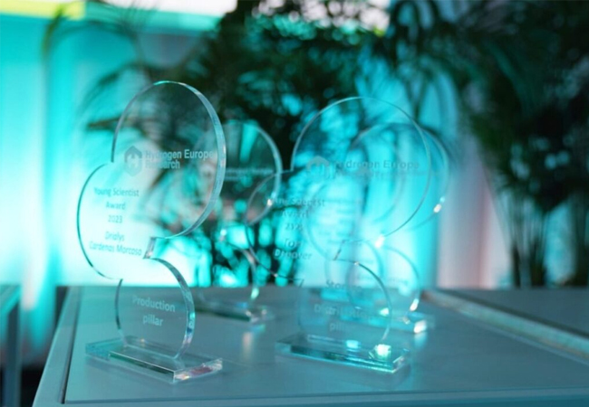 PB: Nachwuchswissenschaftlerpreis: Der Nachwuchswissenschaftlerpreis, der jährlich von Hydrogen Europe Research vergeben wird, würdigt vielversprechende Nachwuchsforscher (bis 35 Jahre) unserer Mitgliedsorganisationen. Diese Personen haben einen bedeutenden persönlichen Beitrag zu Wasserstoffprojekten geleistet. Mit diesem Wettbewerb möchte Hydrogen Europe Research die Leistungen von Studierenden, Doktoranden, Postdoktoranden und Nachwuchsforschern ins Rampenlicht rücken und ihre Teilnahme an Projekten der Clean Hydrogen Partnership fördern. Darüber hinaus soll das Ziel verfolgt werden, aufstrebende Talente für den Wasserstoff- und Brennstoffzellensektor zu gewinnen. Der Wettbewerb konzentriert sich jedes Jahr auf vier zentrale Säulen, die auf den Rahmen der Clean Hydrogen Partnership abgestimmt sind. In jeder Säule wird ein Nachwuchswissenschaftler ausgezeichnet, ein weiterer zum „Besten Forscher des Jahres“ gekürt. Die Preisverleihung findet in der Regel persönlich im Rahmen der Wasserstoffwoche in Brüssel statt. Die fünf Gewinner erhalten jeweils 1000 Euro und eine Trophäe. / ©: Hydrogen Europe Research